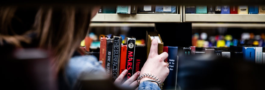 Student taking a book off the shelf.