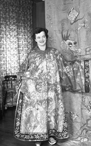 Lucy Little models jewelled Chinese coat in front of silk wall hanging brought home by Mr. and Mrs. George Harris and Miss Amelia (Milly) Harris as souvenirs from their 1897 world tour. London Free Press Collection of Photographic Negatives, March 2, 1960