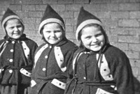 Three girls wearing matching winter coats and hats. Black and white still from Massecar film, 1947-1949, location unknown.