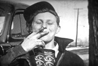 Young person smoking a cigarette. Black and white still, Massecar film 1947-1949, location unknown.