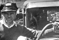 Man filling a car up with fuel. Black and white still from Massecar film, 1947-1949, location unknown.