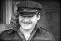 Man in a hat, smiling. Black and white still from Massecar film, 1947-1949, location unknown.