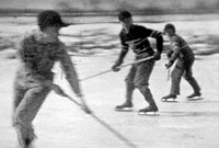 Three children playing hockey on a frozen pond. Black and white still from Massecar film, 1947-1949, location unknown.