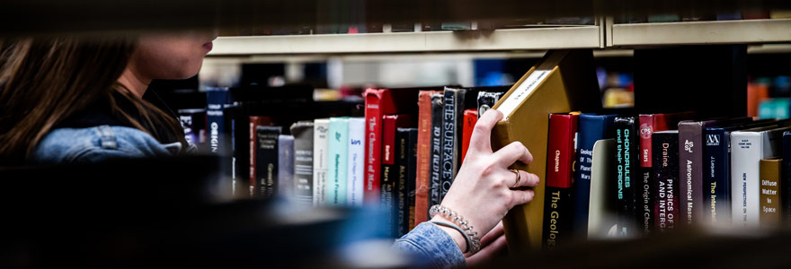 Student taking a book off a shelf.