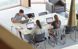 Students studying at a table using laptops