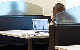 Student seated in a booth working, on a laptop