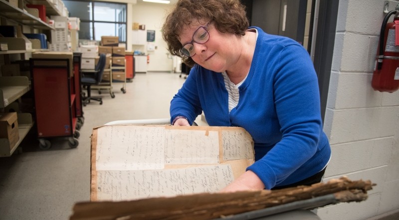 Archivist Anne Quirk examines a historical ledger from the newly donated LHSC archives